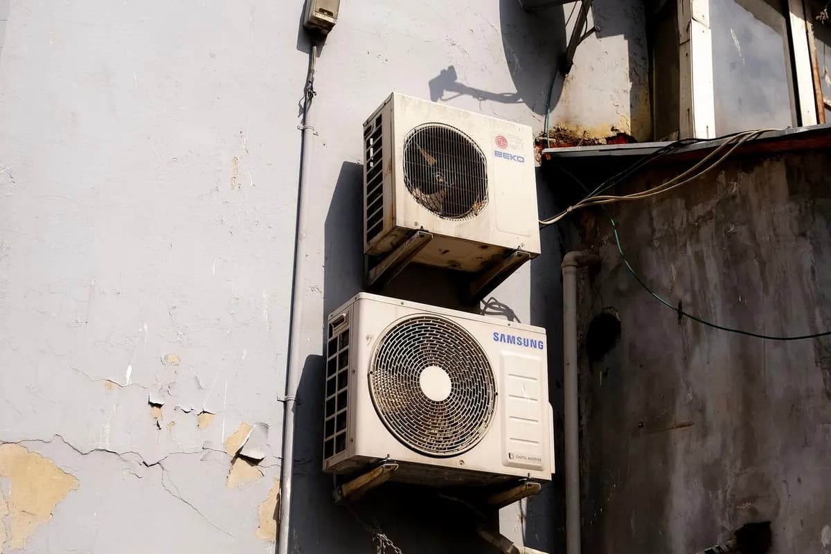 Weathered outdoor air conditioning units on a stained wall